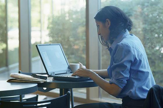 Photo of a woman sitting at a table looking at her computer