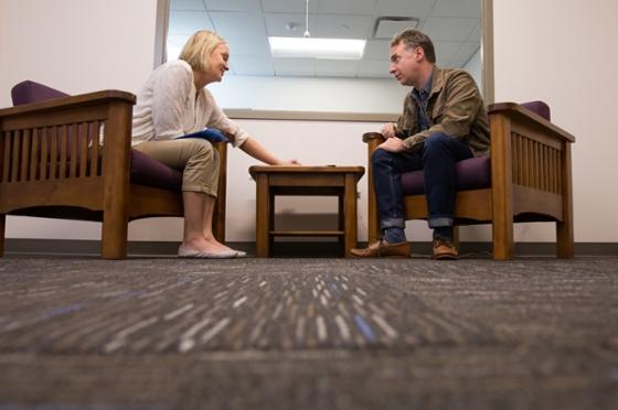 Photo of a Chatham University psychology student sitting across from a man with a clipboard on her lap. 